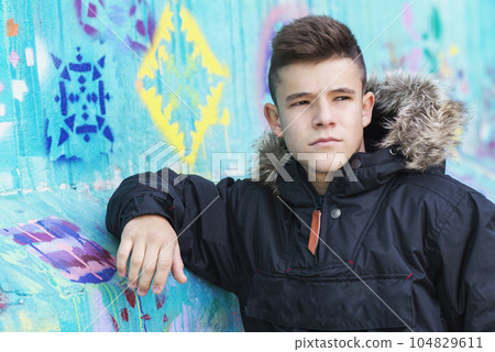 Portrait of teenager leaning against a wall in the street, looking away Portrait of teenager leaning against a wall in the street, looking away 104829611