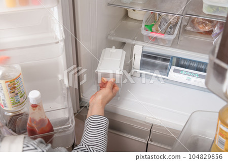 [Housewife taking out the water tank from the refrigerator] 104829856