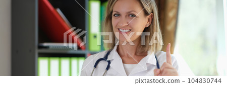 Female doctor holds chocolate cake in her hand and reminds not to eat junk food. 104830744