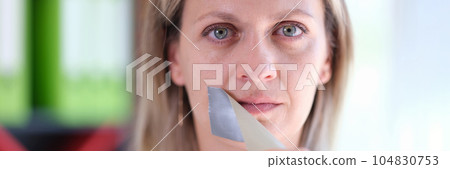 Woman removes adhesive tape covering her mouth. Woman removes adhesive tape covering her mouth. 104830753