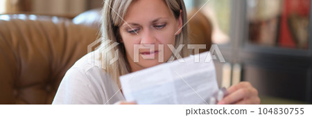 Woman with package of medical pills reads leaflet with instructions for taking pills. Woman with package of medical pills reads leaflet with instructions for taking pills. 104830755