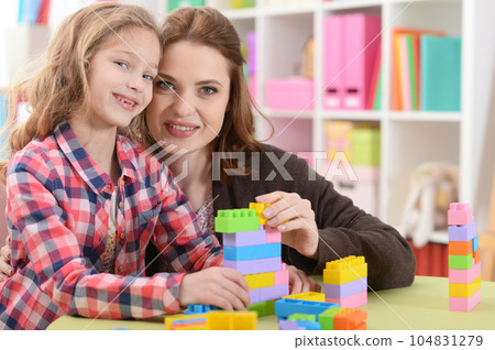 Cute little girl and her mother playing colorful plastic blocks Cute little girl and her mother playing colorful plastic blocks 104831279
