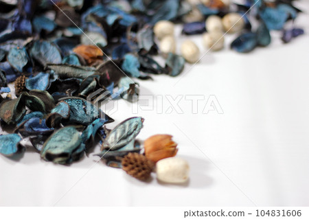 A mix of dry flowers, leaves, petals, and other plant parts. Potpourri background. Purple and blue tone leaves, white color and wood grain background shot. 104831606