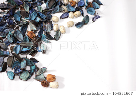 A mix of dry flowers, leaves, petals, and other plant parts. Potpourri background. Purple and blue tone leaves, white color and wood grain background shot. 104831607