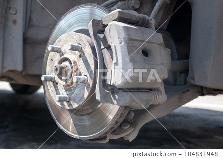 Disc brake of the vehicle for repair, in process of new tire replacement. Car brake repairing in garage. Replacement of brake pads. Suspension of car for maintenance brakes and shock absorber systems. Disc brake of the vehicle for repair, in process of new tire replacement. Car brake repairing in garage. Replacement of brake pads. Suspension of car for maintenance brakes and shock absorber systems. 104831948