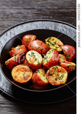 Herbs Garlic Potatoes in black bowl, top view 104832580