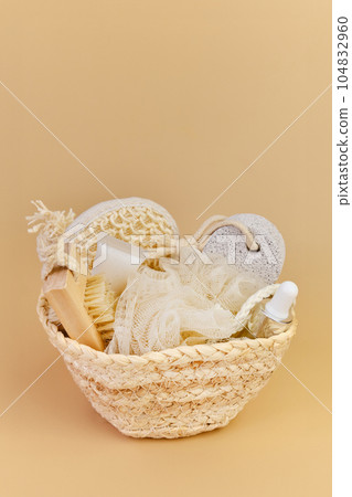 Bath accessories set in wicker basket on a beige background. 104832960