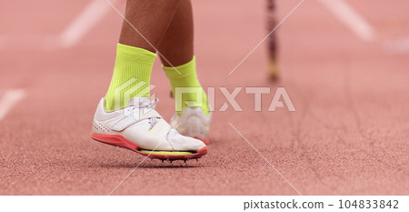 Pole vaulter prepares for jump, detail of sports shoes spikes 104833842