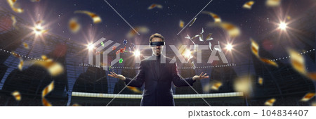 Casino. Handsome businessman in VR glasses standing on 3D sport arena with many chips, tokens. Online game Casino. Handsome businessman in VR glasses standing on 3D sport arena with many chips, tokens. Online game 104834407