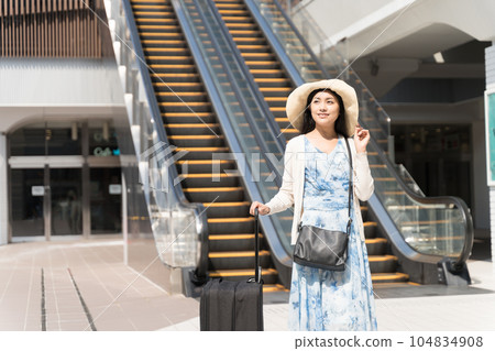 A woman walking with a suitcase in front of an escalator Travel image 104834908