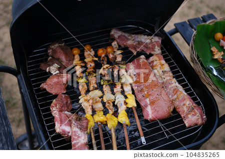 Delicious BBQ pork ribs and meat skewer over the coals. Food, tourism recreation outside and camping concept Delicious BBQ pork ribs and meat skewer over the coals. Food, tourism recreation outside and camping concept 104835265