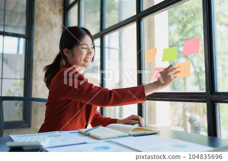 Beautiful young teen asian businesswoman using note pad thinking with planning working on financial document, tax, exchange, accounting and Financial advisor. 104835696