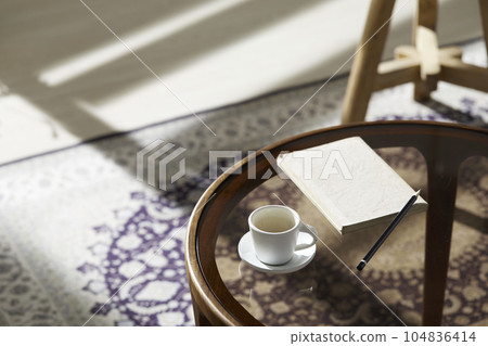This room has a calm atmosphere with natural light. There are clay pots, glass bottles, coffee and various objects on the table. 104836414