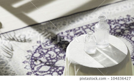 This room has a calm atmosphere with natural light. There are clay pots, glass bottles, coffee and various objects on the table. 104836427