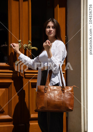 Street photo of young beautiful woman wearing stylish classic clothes. Female fashion concept. 104836756