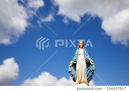 Assumptio of Mary. Virgin Mary statue with the blue sky with white clouds. 104837857