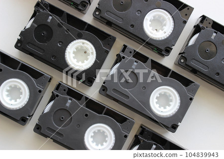 Video tapes format are laid out in even rows similar to bricks on a white surface  104839943