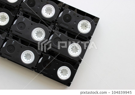 Huge video cassette laid out from small several VHS cassettes on white surface  104839945