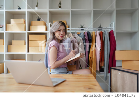 Asian female fashion designer sketches the design of a new dress in a fashion studio 104841172