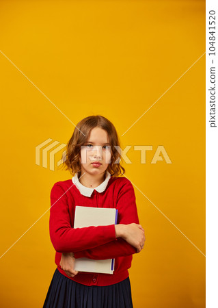 Sad teenage schoolgirl holding hugs the book in hand 104841520