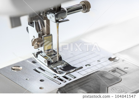 Modern white sewing machine presser foot closeup, macro Modern white sewing machine presser foot closeup, macro 104841547
