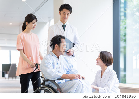 Doctor talking to inpatient in wheelchair in hospital 104841950