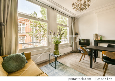 a living room with a table, chairs and a tv in the corner of the room looking out onto the street a living room with a table, chairs and a tv in the corner of the room looking out onto the street 104843166