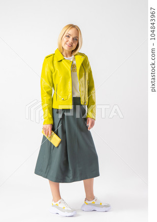 A young blonde woman in a stylish casual outfit with a small leather clutch. A young blonde woman in a stylish casual outfit with a small leather clutch. 104843967