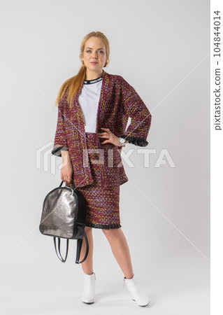 A young blonde in a casual warm office outfit, with a bag in her hands. A young blonde in a casual warm office outfit, with a bag in her hands. 104844014