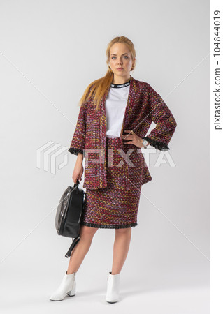 A young blonde in a casual warm office outfit, with a bag in her hands. A young blonde in a casual warm office outfit, with a bag in her hands. 104844019