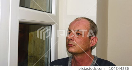 Depressed middle age man sitting near window 104844286