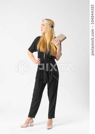 A young blonde woman in a smart black trouser suit with a clutch bag in her hand A young blonde woman in a smart black trouser suit with a clutch bag in her hand 104844385