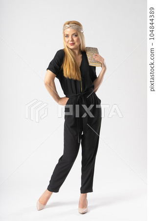 A young blonde woman in a smart black trouser suit with a clutch bag in her hand A young blonde woman in a smart black trouser suit with a clutch bag in her hand 104844389