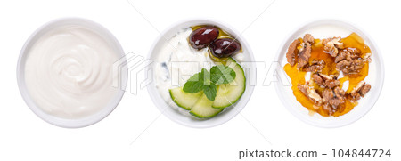 Cream yogurt, tzatziki, and Greek yogurt with honey and roasted walnuts, in white bowls. Stirred yoghurt (left), Greek dip sauce, mixed with cucumber and garlic (center), and Yiaourti me meli (right). 104844724