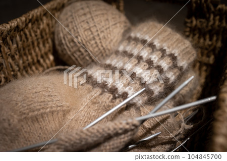Needlework in a wicker basket: knitting wool socks. Needlework in a wicker basket: knitting wool socks. 104845700