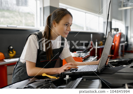 Back view on woman auto engineer doing computer diagnostic 104845994