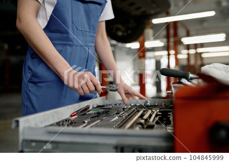 Closeup woman mechanic choosing correct tool for car repair Closeup woman mechanic choosing correct tool for car repair 104845999
