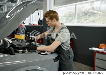 Male mechanic with wrench working under opened car hood Male mechanic with wrench working under opened car hood 104846022