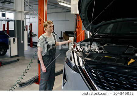 Young man mechanic raising broken car up on automated lifting machine Young man mechanic raising broken car up on automated lifting machine 104846032