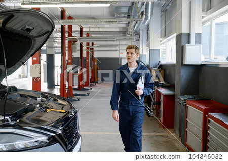 Professional handsome male car mechanic walking along service station 104846082