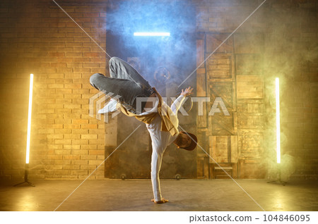 Young male professional dancer b-boying on studio stage Young male professional dancer b-boying on studio stage 104846095