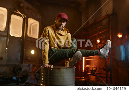 Young male breakdancer dancing on steel barrel tank 104846159