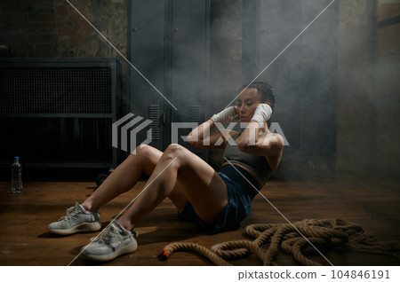 Attractive woman boxer doing abs crunch workout during training at gym 104846191