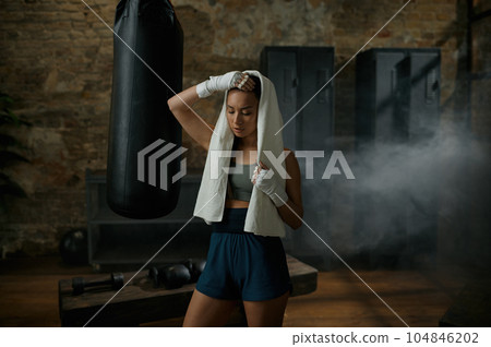 Tired sporty attractive woman boxer wearing towel on head after workout 104846202