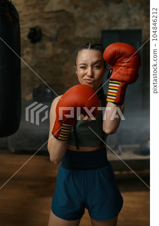 Attractive female boxer looking through red boxing gloves 104846212