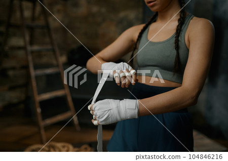 Woman boxer wrapping her hands in bandage Woman boxer wrapping her hands in bandage 104846216