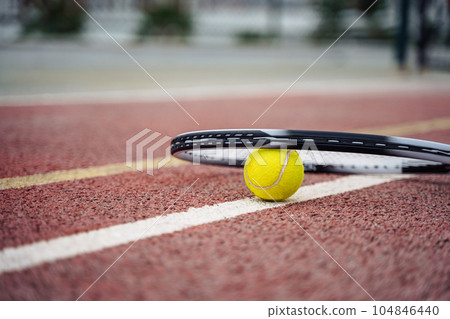 Closeup view on tennis ball and racket racquet lying on acrylic tennis hard court surface with empty blank copy space 104846440