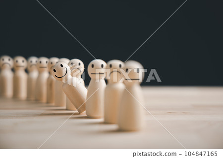 Wooden figure representing customer service rating. Hand picked in a crowd of people. HR selects a positive leader with a happy and smiling face to guide the team towards success in business concept. 104847165