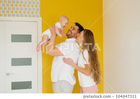 Happy parents hold their baby son in their arms, look at him and smile 104847311
