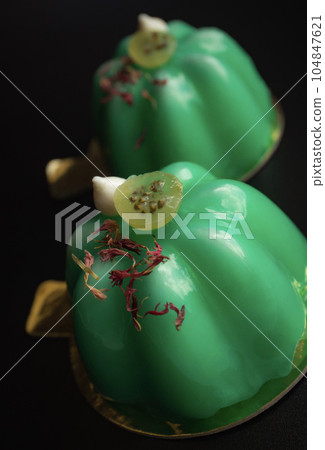 Green gooseberry mousse modern desserts with mirror glaze topped with meringue kisses and berries on black background close up 104847621